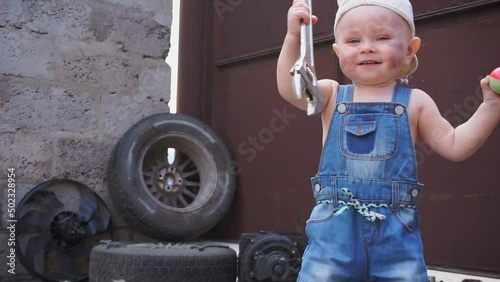 baby mechanic picks up wrench and smiles and starts walking towards camera