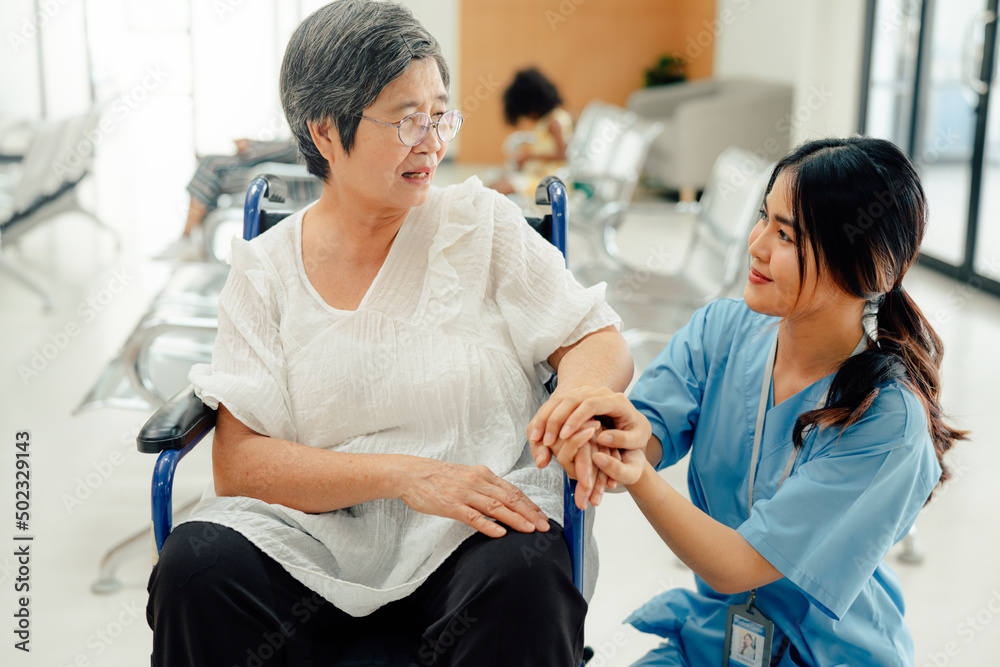 Obraz premium Asian nurse taking care and talking mature female patient sitting on wheelchair in hospital. Healthcare concept.