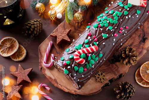 Traditional chocolate trunk cake or log cake on table with Christmas decorations photo