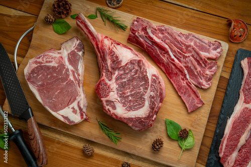 Mixed fresh meat Tomahawk beef, Cross Cut Short Ribs beef, Sliced brisket beef, T-bone steak beef on wooden background. photo