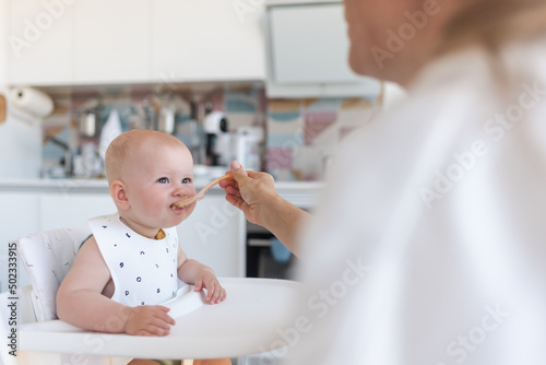 baby's first feeding, mom feeds a baby with a spoon