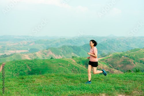 Asian women runner training on a high mountain. The back view is high mountain, beautiful scenery. In the evening the air is fresh and atmosphere is good.