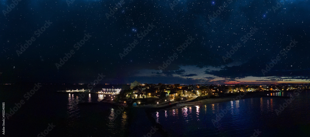 Panorama of the city of Pomorie with hotels and lights washed by the Black Sea under the starry sky in Bulgaria
