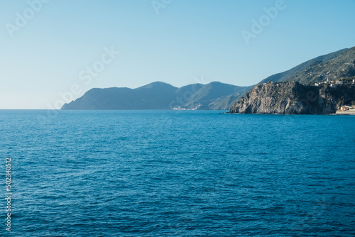 Beautiful seascape with blue sky, smooth water surface and rocky cliffs in Liguria coastal area. Popular italian travel destination.