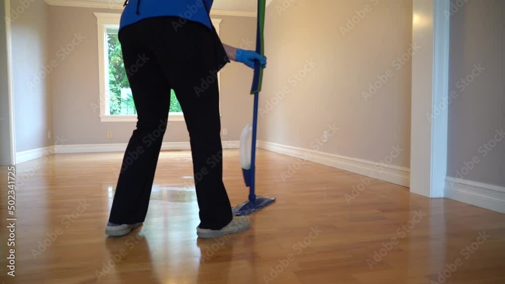 Someone cleaning a wooden floor in an empty house. Professional cleaning service. Someone cleaning a wooden floor in an empty house. Professional cleaning service.