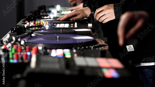 Close up of three men DJs playing electronic party music on vinyl cd usb player in the studio. Art. Side view of male hands and turntable controlling mixer.