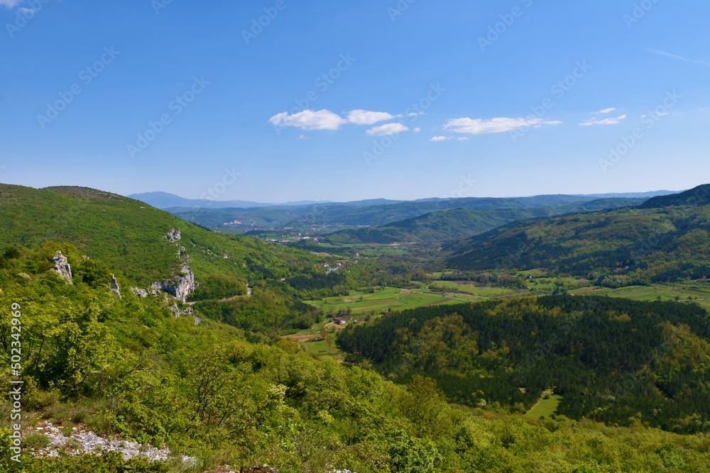 Scenic view of mountains and hills in Istria in Slovenia and a meadow with low growing mediterranean trees near Socerga