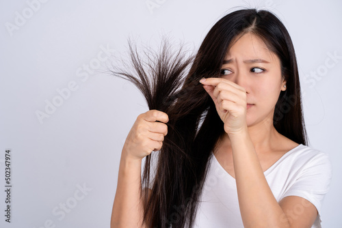 Asian woman with damaged hair. She is stressed and wondering something isolated on a white background.