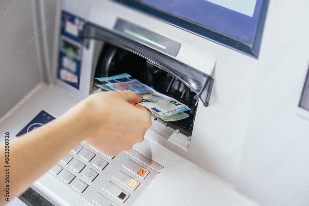 Close up of a woman's hand withdrawing cash, euro bills from the ATM bank machine. Finance customer and banking service concept Close up of a woman's hand withdrawing cash, euro bills from the ATM bank machine. Finance customer and banking service concept