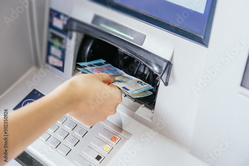 Close up of a woman's hand withdrawing cash, euro bills from the ATM bank machine. Finance customer and banking service concept photo