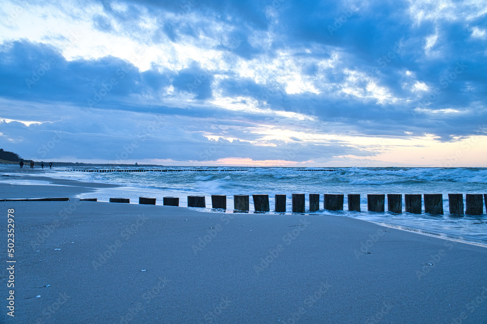 sunset on the beach of the Baltic Sea. Groynes reach into the sea. blue hour