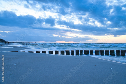Fototapeta Naklejka Na Ścianę i Meble -  sunset on the beach of the Baltic Sea. Groynes reach into the sea. blue hour