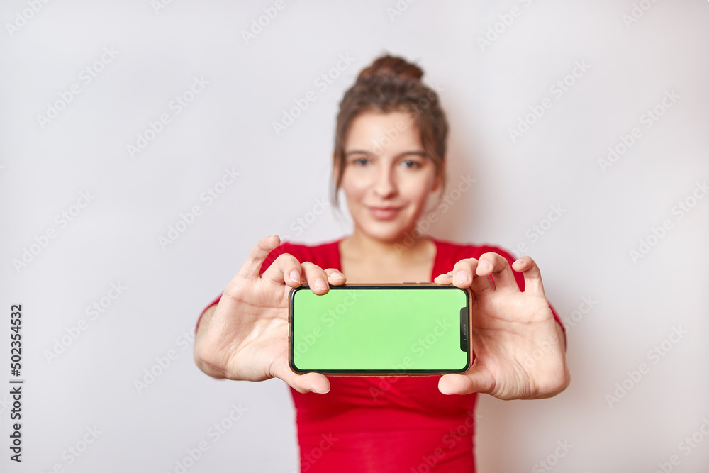 Pretty girl holding a smartphone with a green display. Demonstration of the image on the smartphone screen. Pretty girl holding a smartphone with a green display. Demonstration of the image on the smartphone screen.