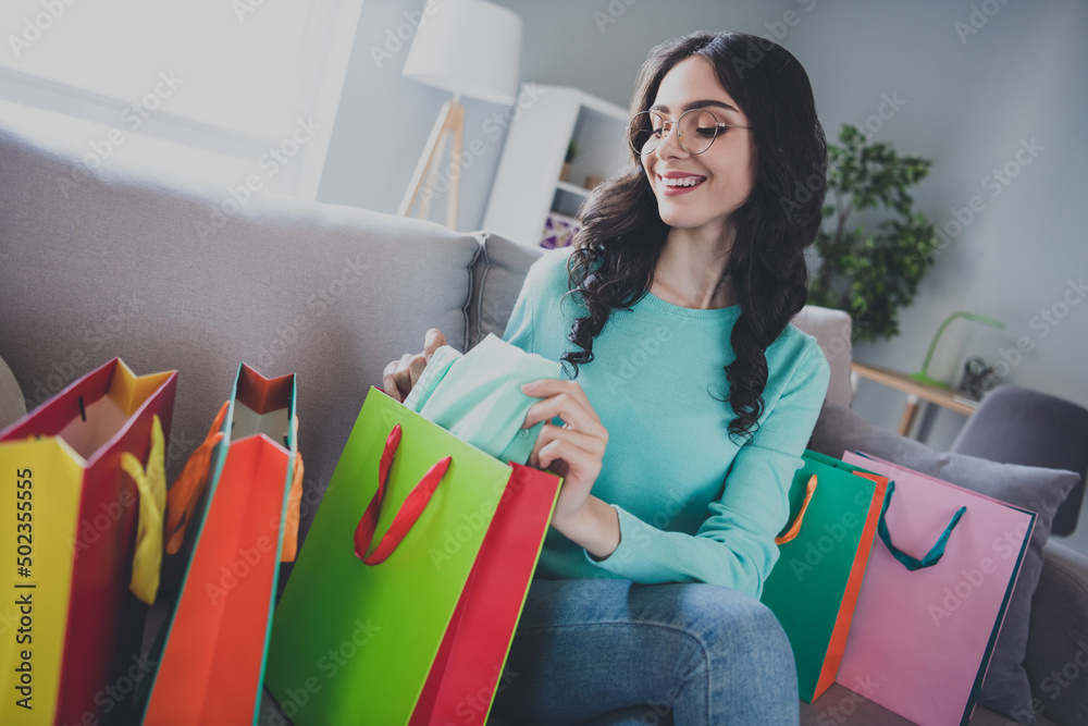 Photo of young cheerful pretty girl receive gift shopping bags sit divan boutique discount new collection indoors Photo of young cheerful pretty girl receive gift shopping bags sit divan boutique discount new collection indoors