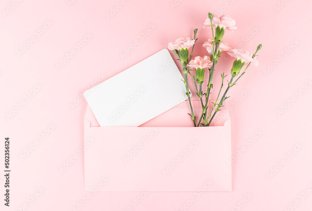 Blank card in pink envelope with carnations on pink background. Copy space Blank card in pink envelope with carnations on pink background. Copy space