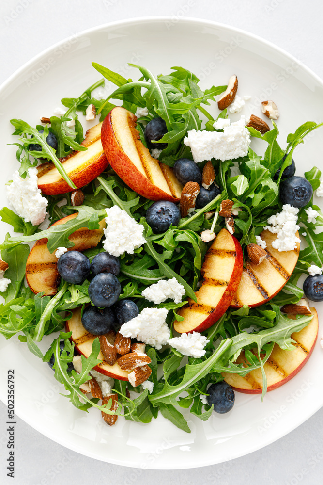 Peach, blueberry and arugula fresh fruit salad with cheese and almond nuts, top view Peach, blueberry and arugula fresh fruit salad with cheese and almond nuts, top view