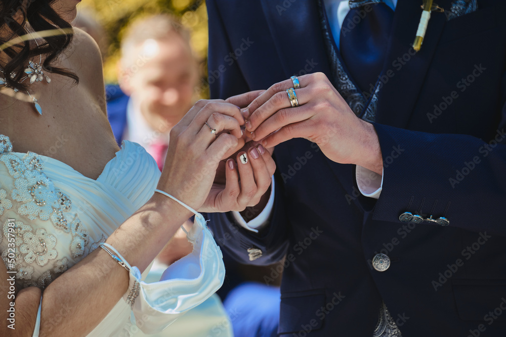 Fototapeta premium Close up of the hands of a bride and groom giving each other wedding rings