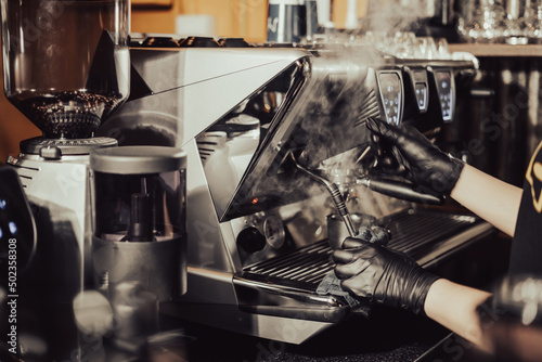 Fotografia, Obraz Close-up of Barista steaming milk for a hot cappuccino with a machine in a coffee shop