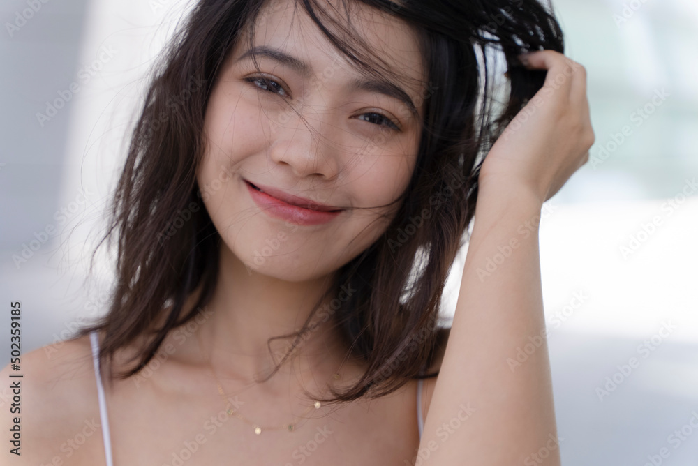 Attractive asian girl wearing white suspenders looking at camera and smiling Attractive asian girl wearing white suspenders looking at camera and smiling