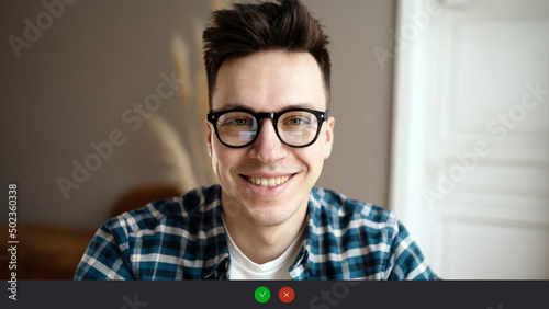 Video call screen a male programmer with glasses looks at the camera and smiles