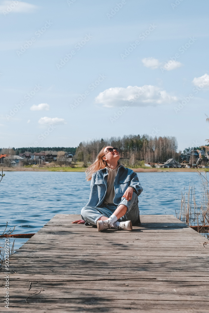 Fototapeta premium travel,adventure,Rest on the lake. A young girl traveler is resting near the water. Eco travel, local travel. Relax, meditation near the water.