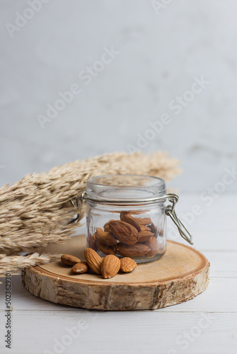 An handful of almonds is on the bottle. There is a branch of pamp. Vertical picture. photo