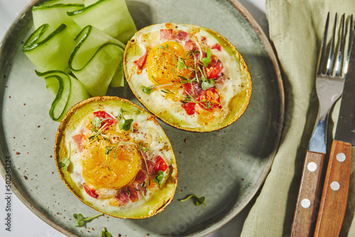 Avocado baked with egg, ham, tomatoes and cheese. Keto lunch recipe. After baking