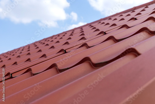 Modern roof made of corrugated red metal tiles roofing
