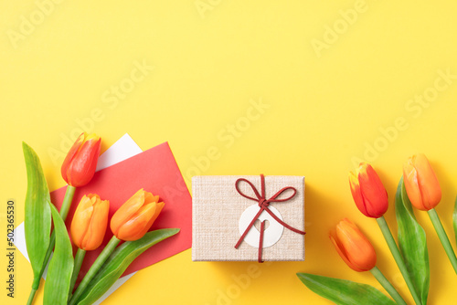 Mother's day background. Top view of gift with tulip bouquet on yellow table background