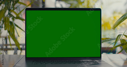 Green Screen Laptop on tabel on balcony with plants on background
