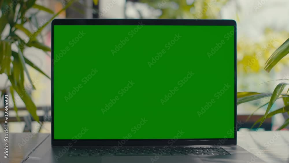 Green Screen laptop on table with green plants on background