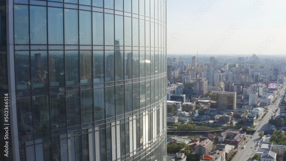 Fototapeta premium Windows of high-rise building on background city. Stock footage. Top view of panoramic Windows of skyscraper on background of city on sunny day. Beautiful Windows of skyscraper at height of bird's