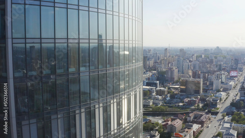 Windows of high-rise building on background city. Stock footage. Top view of panoramic Windows of skyscraper on background of city on sunny day. Beautiful Windows of skyscraper at height of bird s