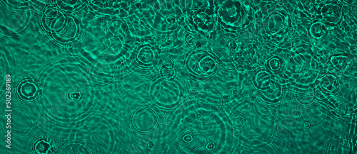 Transparent dark green clear water surface texture with ripples and splashes. Abstract summer banner background Water waves with copy space, top view. Cosmetic moisturizer micellar toner emulsion