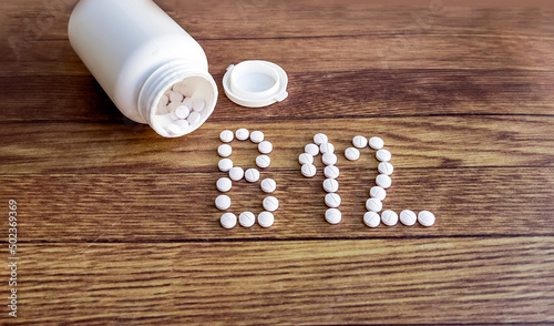 B 12 written with pills . Bottle and b12 pills on wooden background  photo