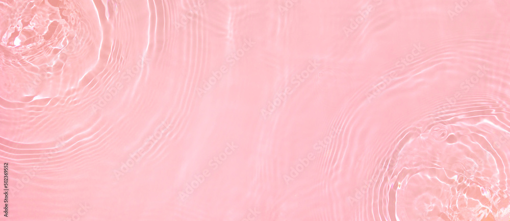 Fototapeta premium Abstract summer banner background Transparent pink clear water surface texture with ripples, splashes. Water waves in sunlight, copy space, top view. Cosmetics moisturizer micellar toner emulsion