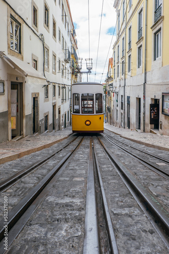 Yellow tram on the street of Lisbon, Portugal, travel destination. Trams in the city of Lisbon. Famous funicular yellow retro tram in the narrow streets of the old town of Lisbon on a sunny summer day