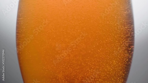 The bubbles in the beer glass slowly rise upwards.