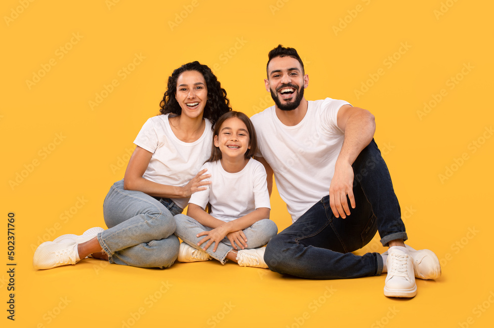Cheerful Middle Eastern Family Of Three Sitting On Yellow Background Cheerful Middle Eastern Family Of Three Sitting On Yellow Background