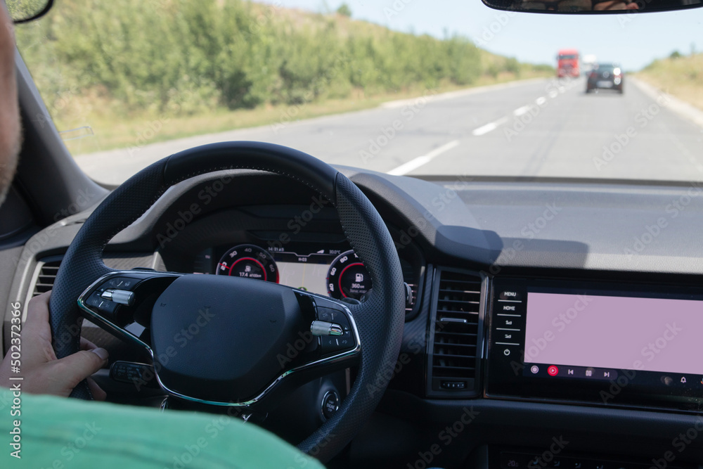 Car interior on the road. Steering wheel, dashboard and on-board display