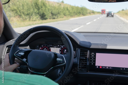 Car interior on the road. Steering wheel, dashboard and on-board display © Alina