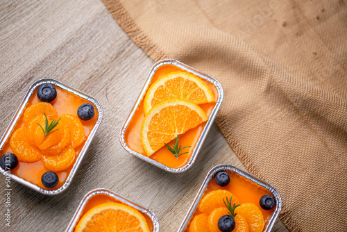 Fresh orange cake topping with orange and blueberry in foil cup.