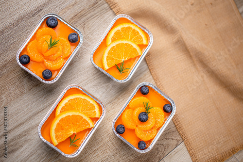 Fresh orange cake topping with orange and blueberry in foil cup.