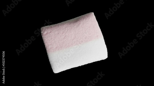 One close-up marshmallow rotates, isolated on a black background