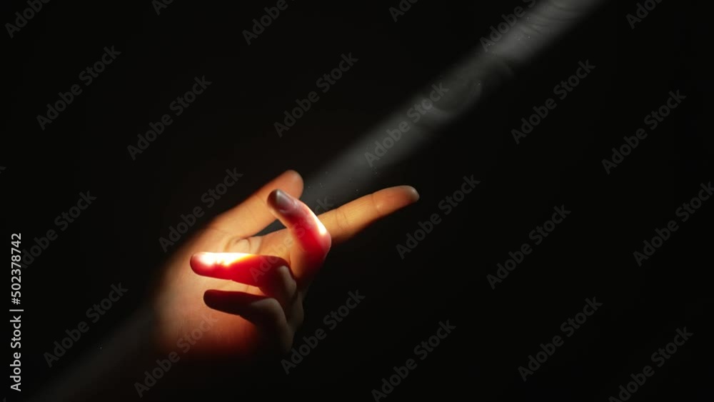 Woman's fingers touching a beam of light