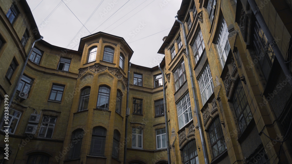 Courtyard of old round building in city. Action. Bottom view of old house with courtyard well on background of sky. Old closed courtyards of houses in St. Petersburg