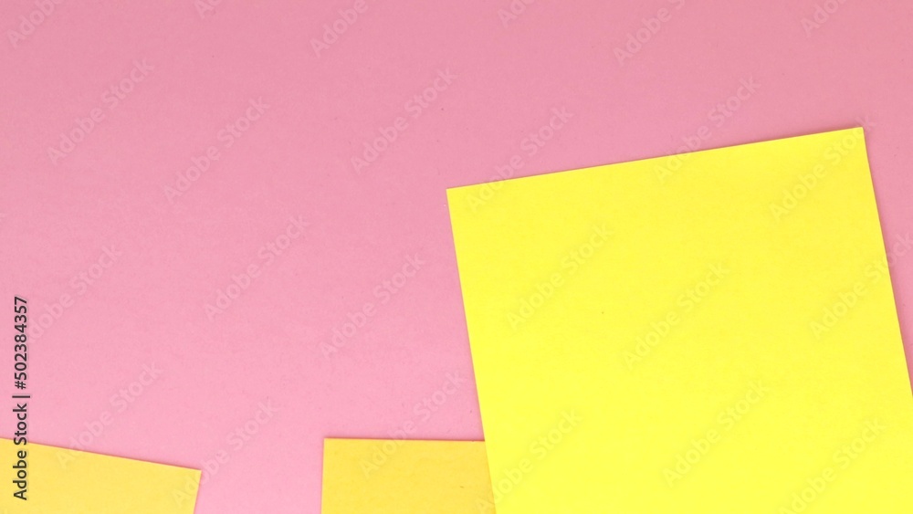 4 to the video, square sheets of yellow note paper fall on a pink paper background, top view 4 to the video, square sheets of yellow note paper fall on a pink paper background, top view