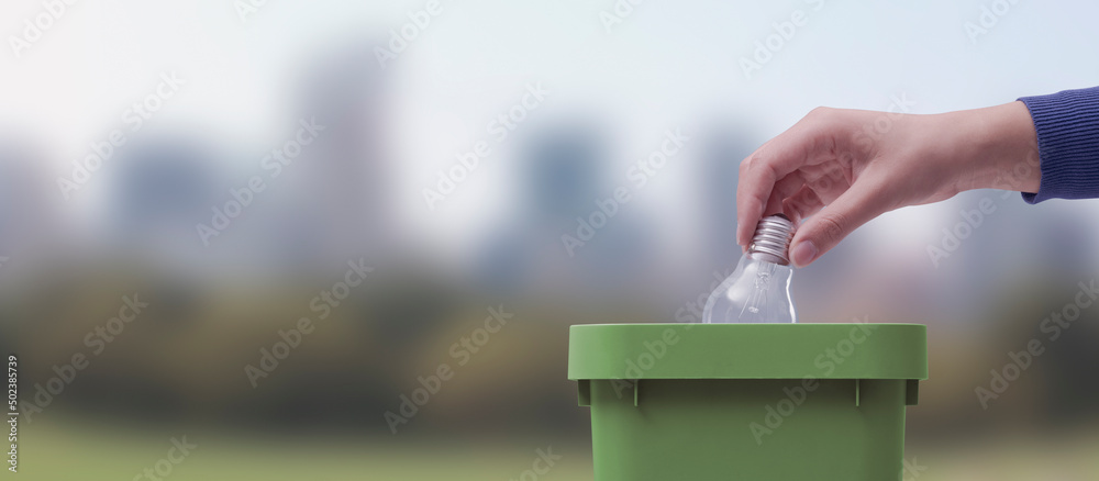 Woman putting a lightbulb in the trash bin - obrazy, fototapety, plakaty 