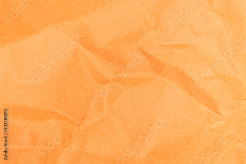 Crumpled orange color paper texture background. Close-up of sheet of paper.