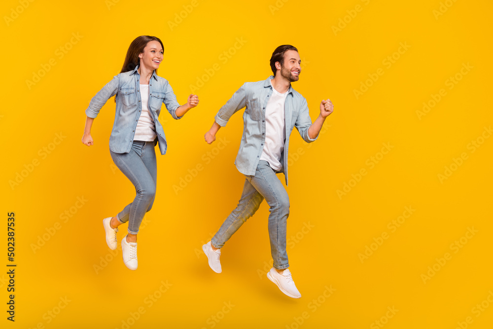 Full length body size view of beautiful handsome cheery people jumping running isolated over bright yellow color background Full length body size view of beautiful handsome cheery people jumping running isolated over bright yellow color background